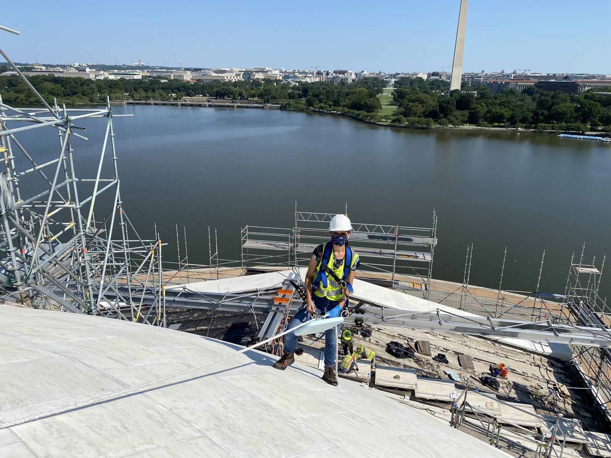 A staff member in blue and neon green stands on the Thomas Jefferson Memorial dome. 