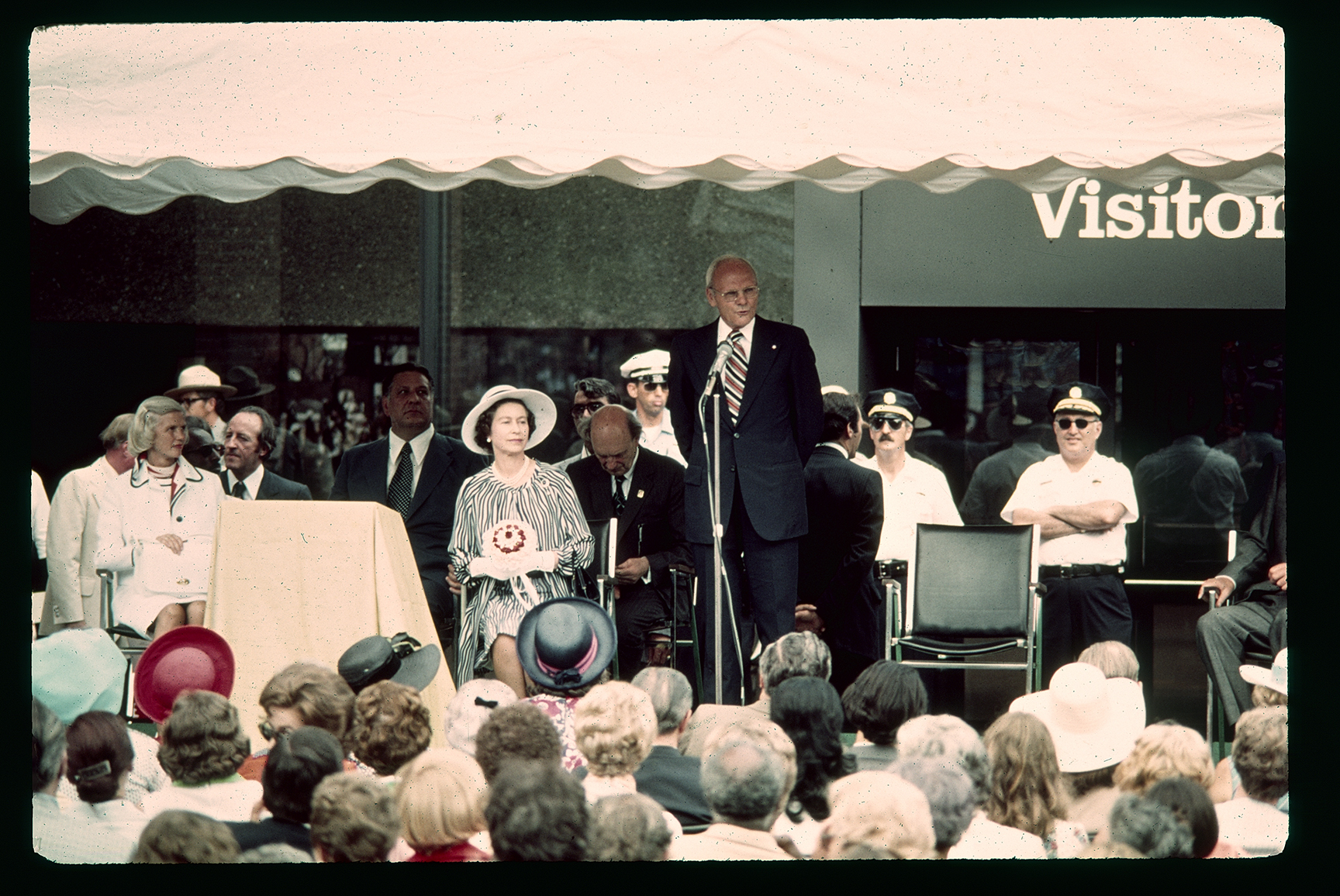 Queen's visit. Old Visitor Center (101 South 3rd Street). Exterior. Looking northeast at 3rd Street entrance. US Secretary of the Interior Thomas S. Kleppe standing and speaking.