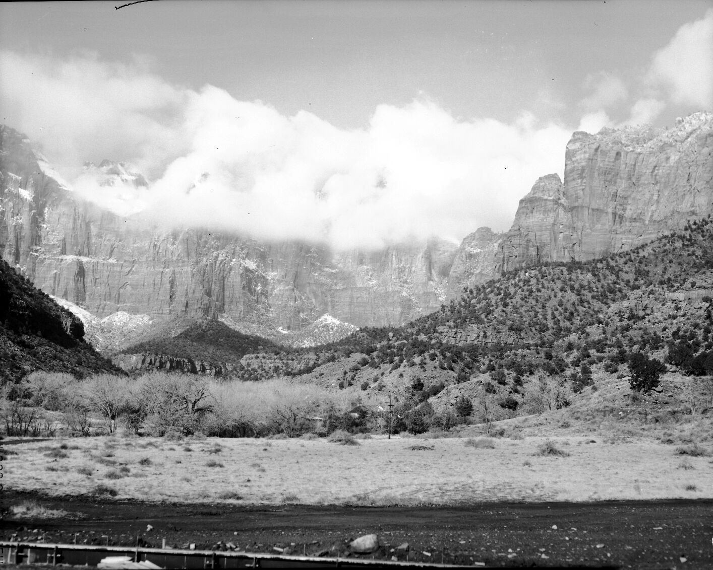 The West Temple and Towers of the Virgin shrouded in clouds and snow, Oak Creek residences in foreground.