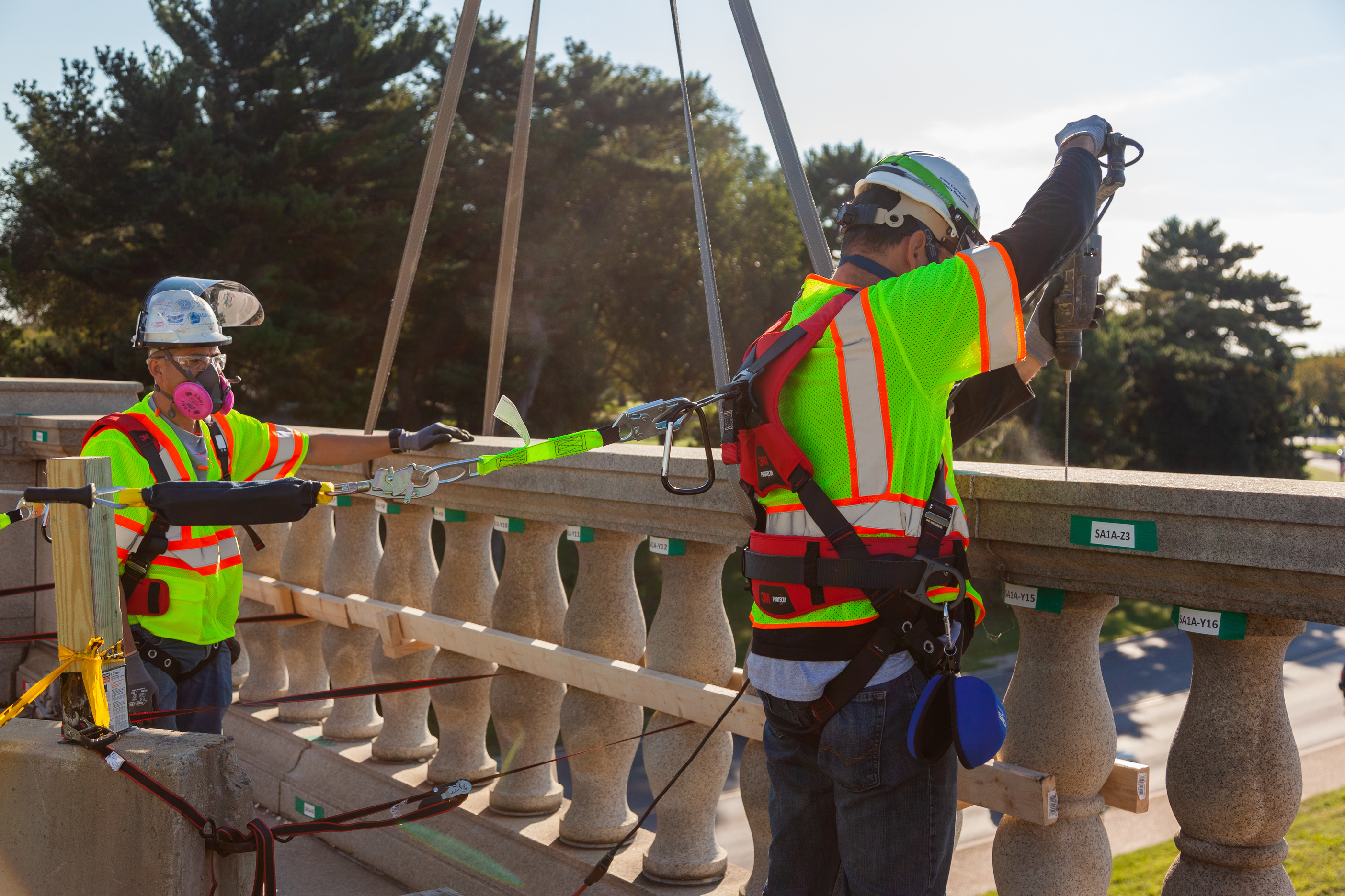 Construction workers in vests work on removing the granite balustrade on Arlington Memorial Bridge