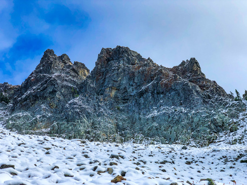 Large rock outcrops rising above a snow-dusted slope. 