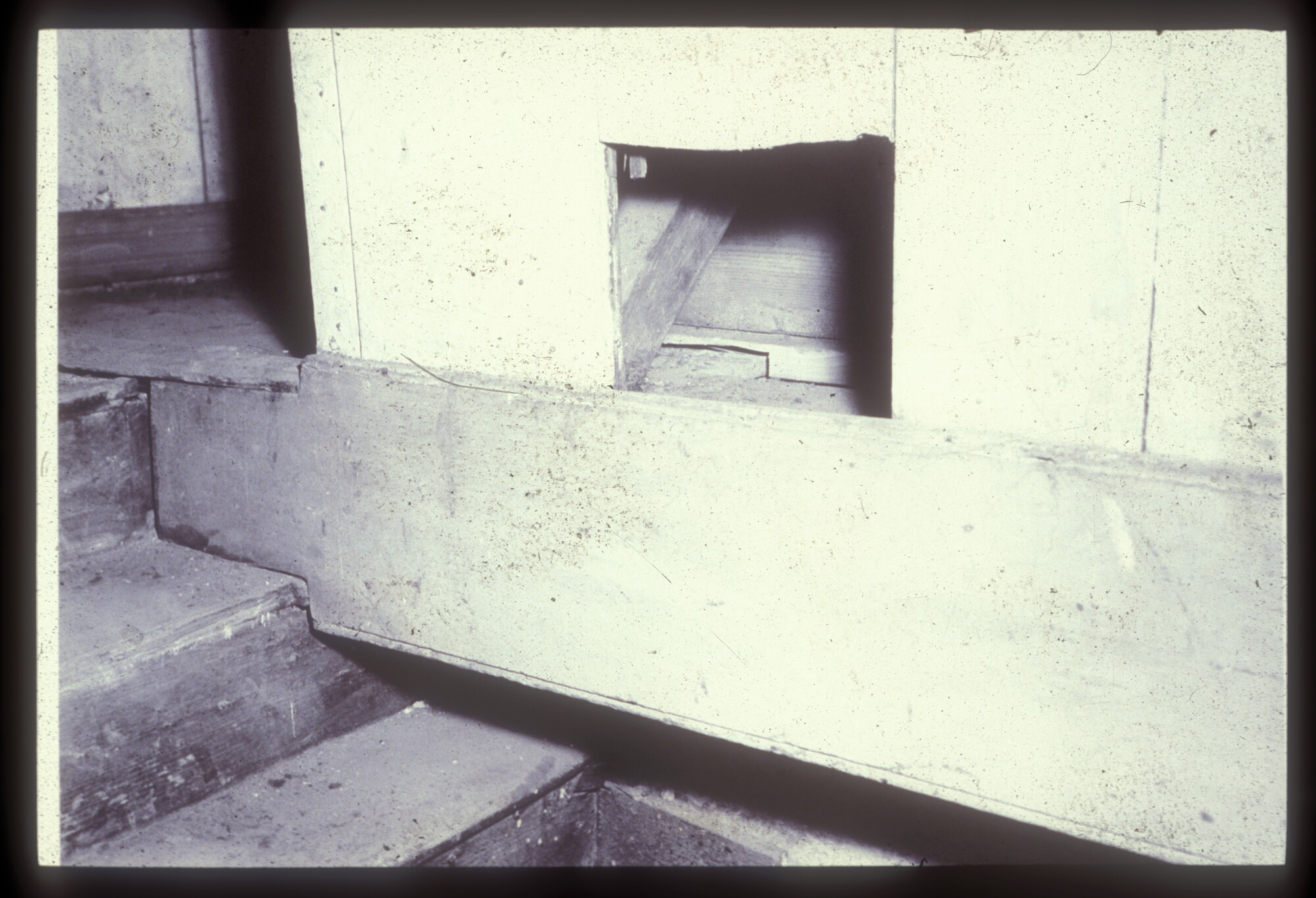 A small hole cut in the all near the top of a staircase