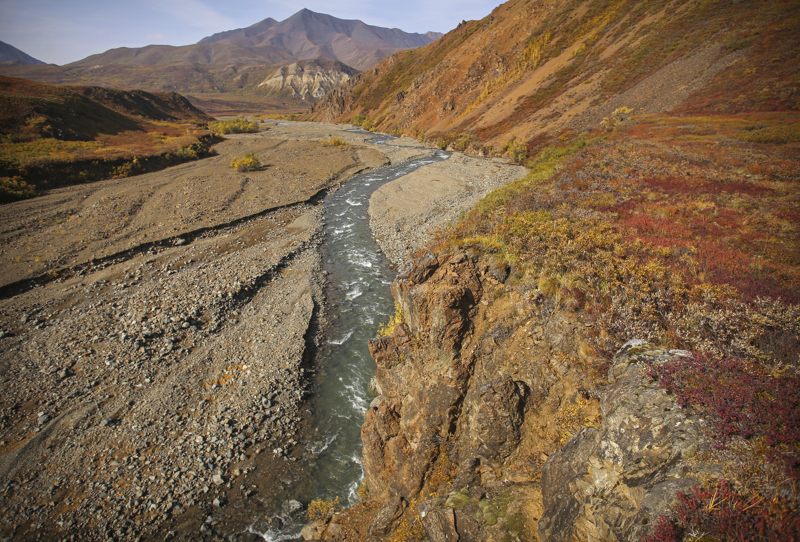a shallow, swift creek flowing at the foot of a mountain