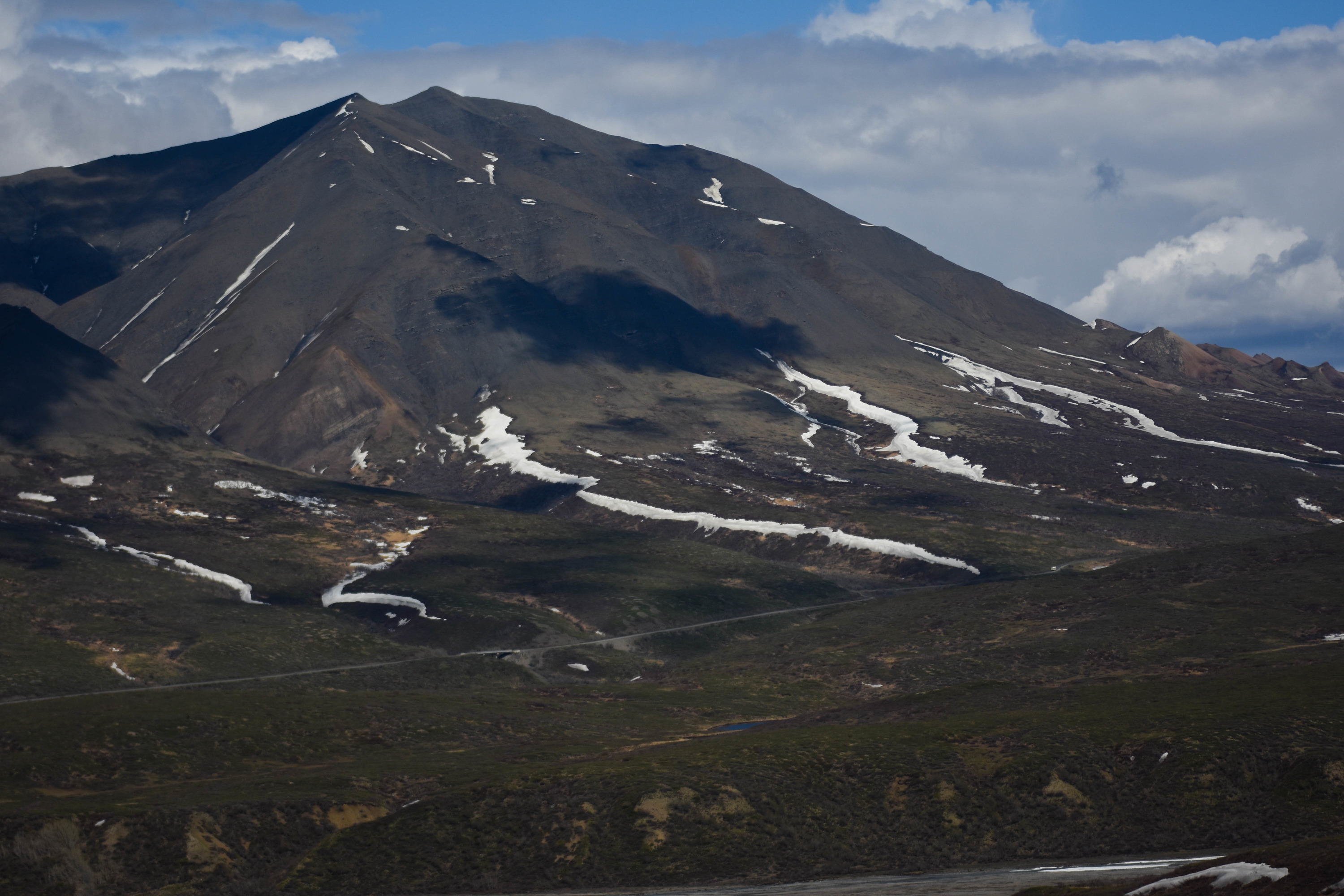 dirt road leading uphill at the foot of a mountain