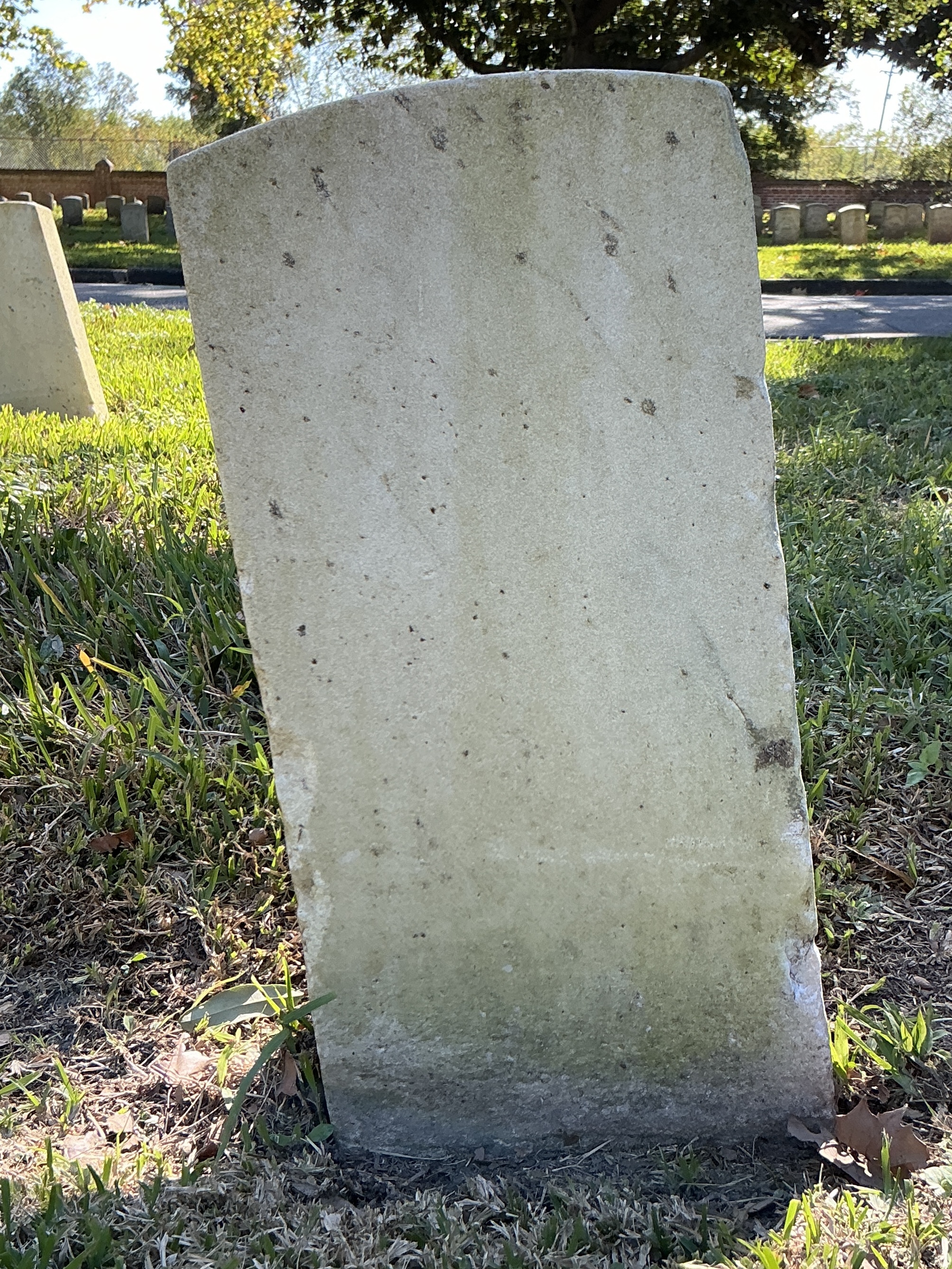 Back of historic upright marble headstone with recessed shield face.