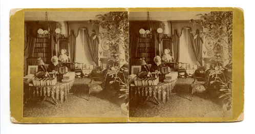 Black and white photograph of old bearded man at table covered in books.