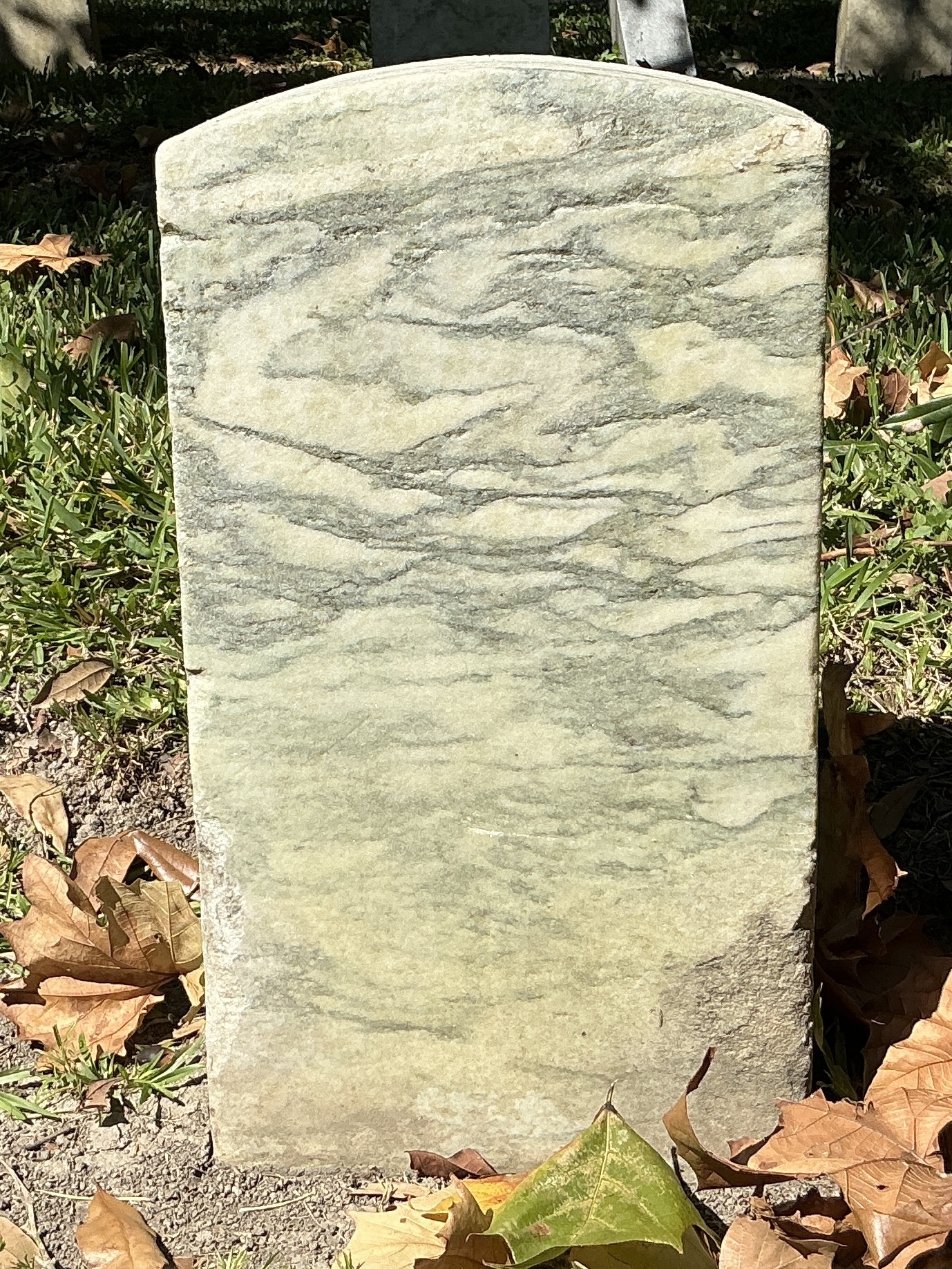 Back of historic upright marble headstone with recessed shield face.