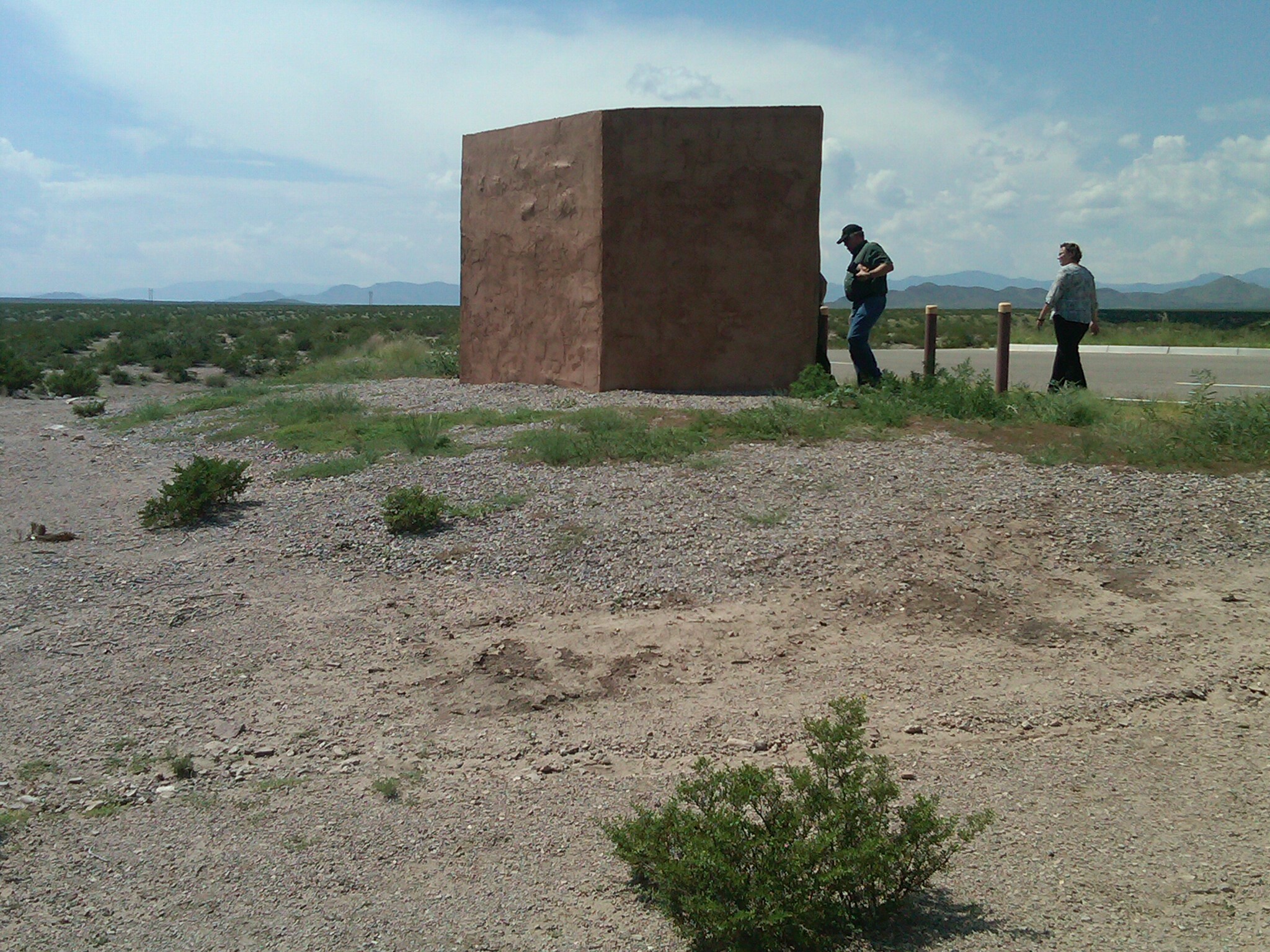 Two people standing next to a structure in the desert.