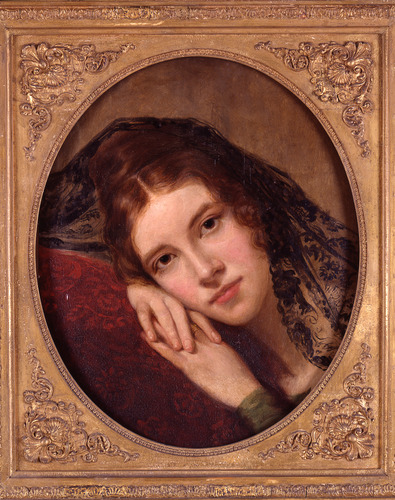 Portrait of young woman wearing black lace scarf leaning her cheek on her folded hands