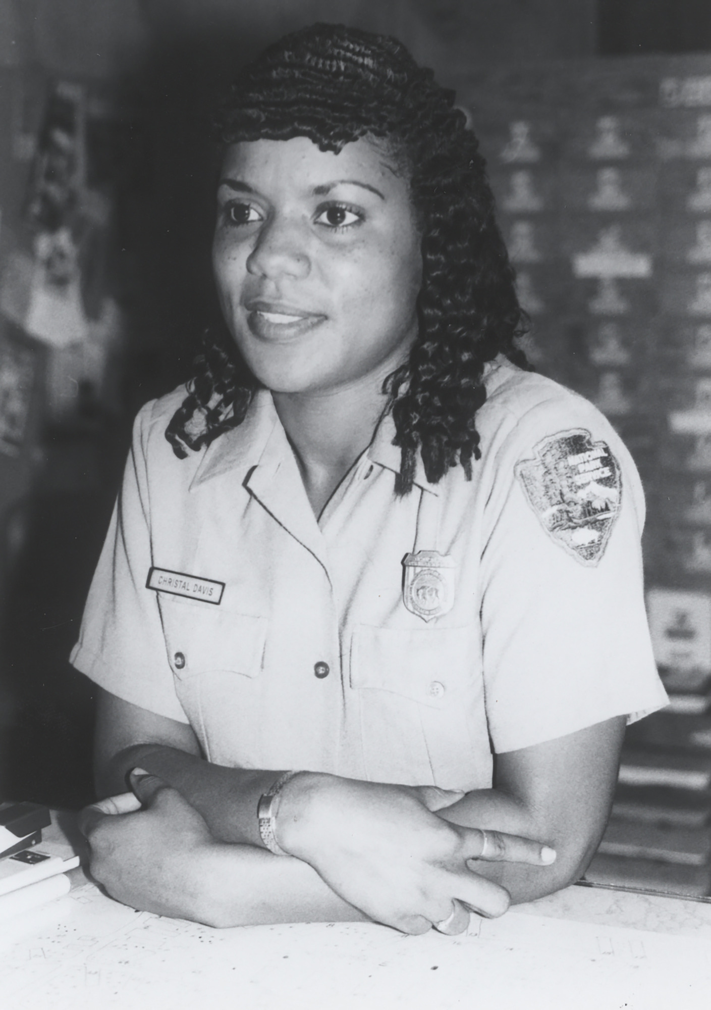 Christal Davis of her in NPS uniform standing behind a desk. 