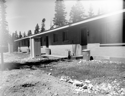 Backside of employee residential multiplex after completion of construction. Fire extinguishers and trash cans flanking back doors.