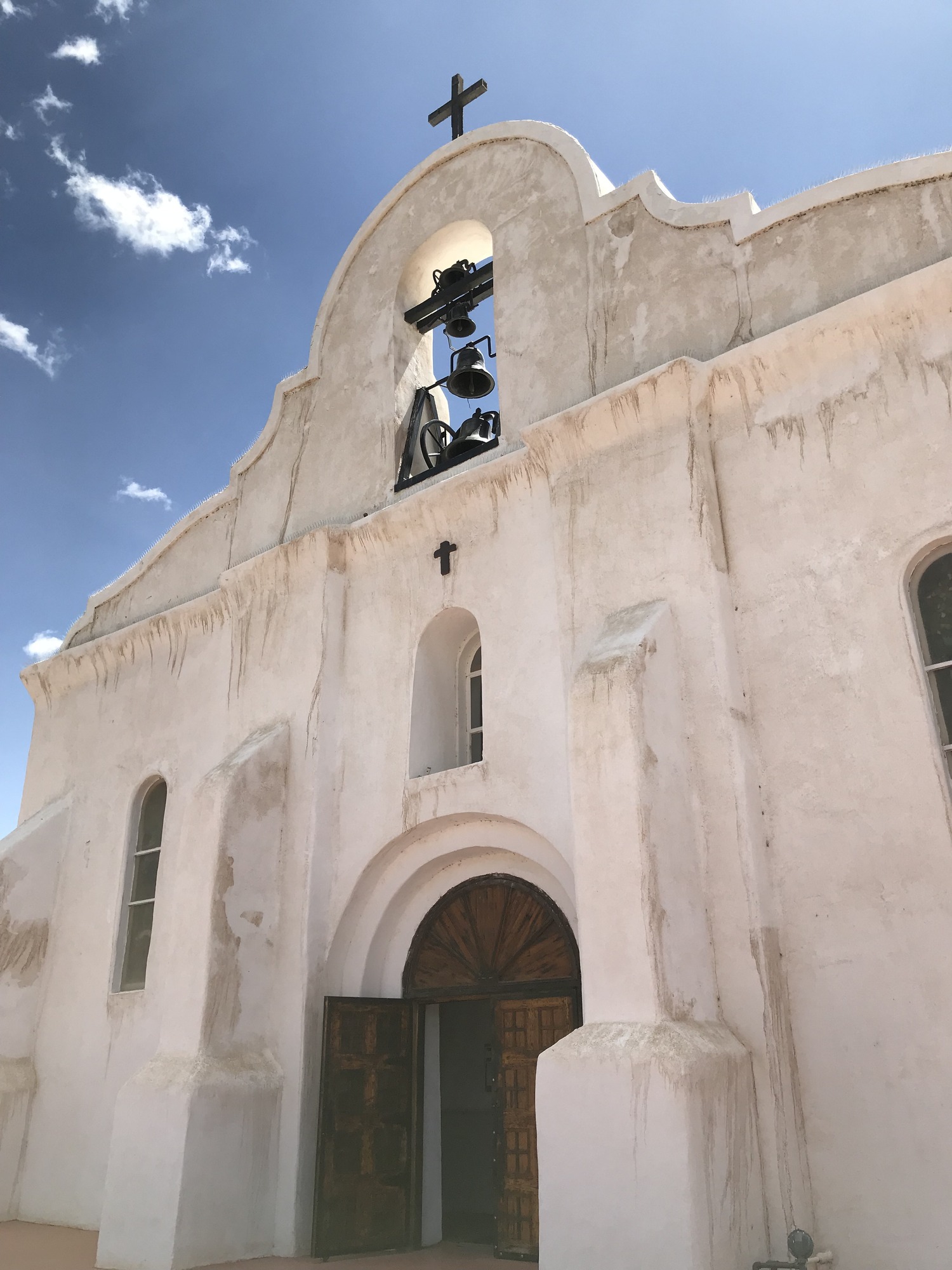 A white church with a cross in front of it.
