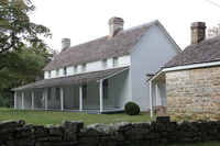 A large white house next to a stone outbuilding