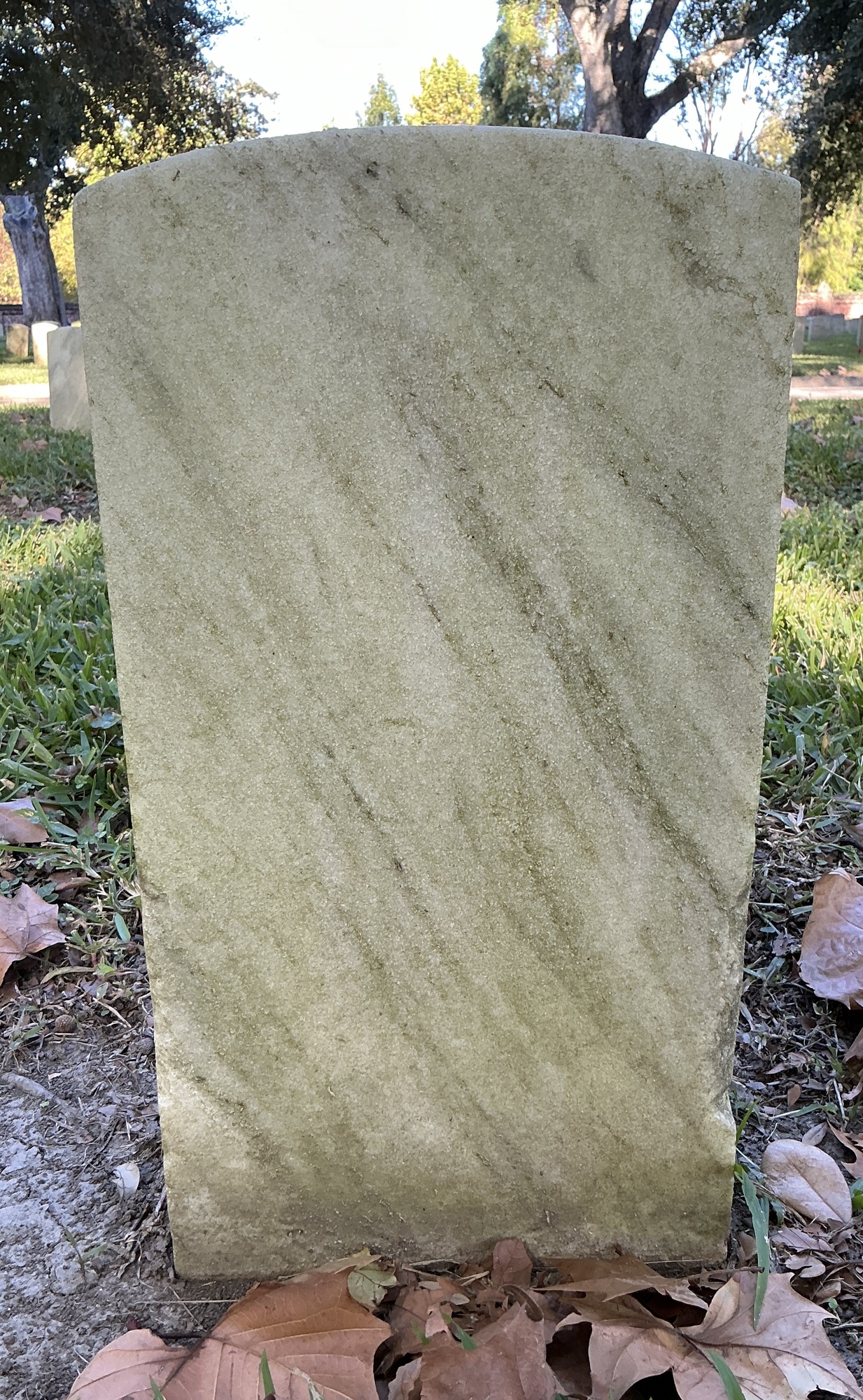 Back of historic upright marble headstone with recessed shield face.