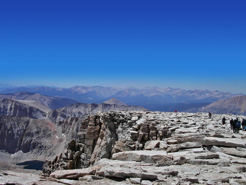 The relatively flat top of Mount Whitney surrounded by the High Sierra Mountains and a clear blue sky.