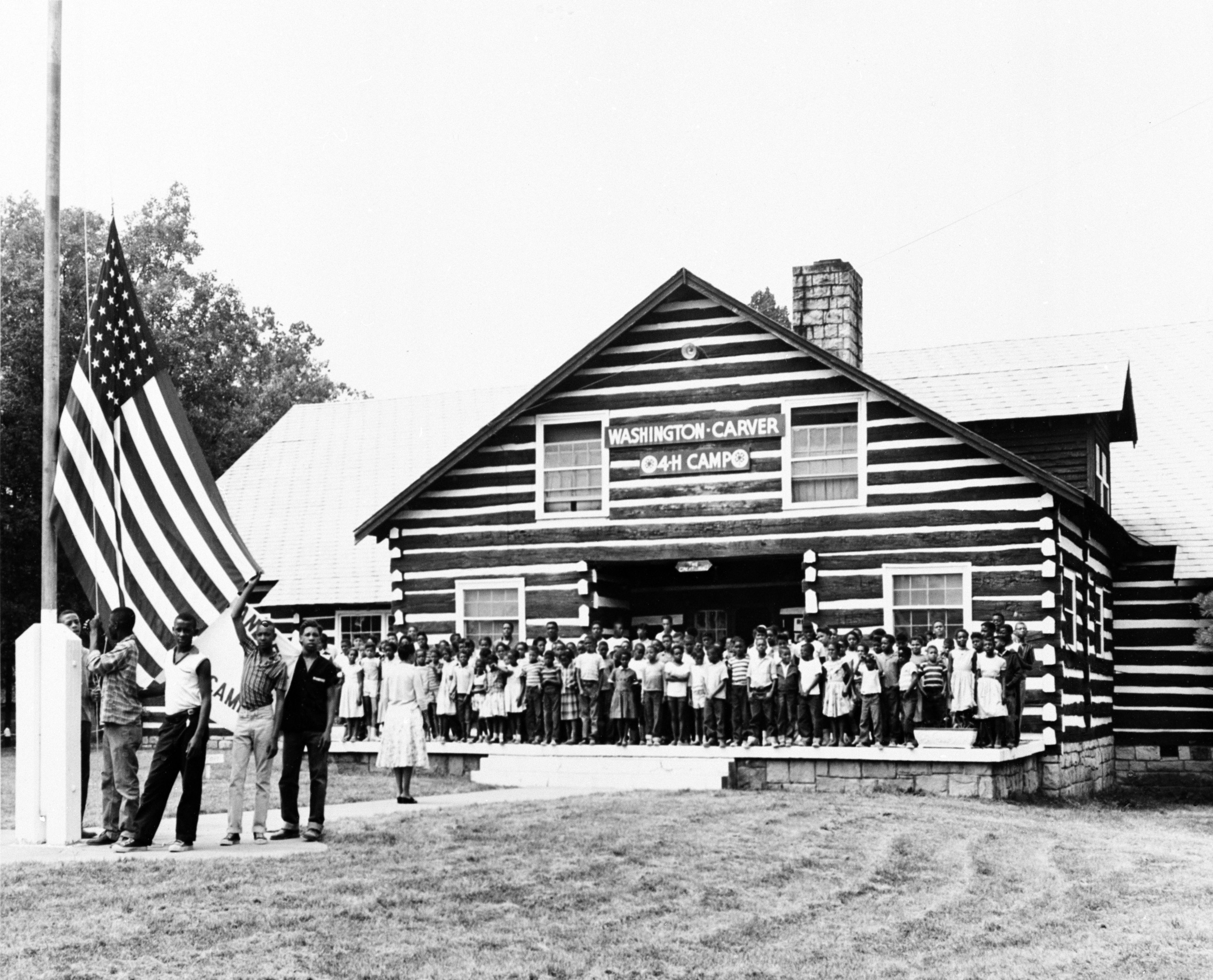 historic black and white photo of children posing in from of a 4-H camp lodge