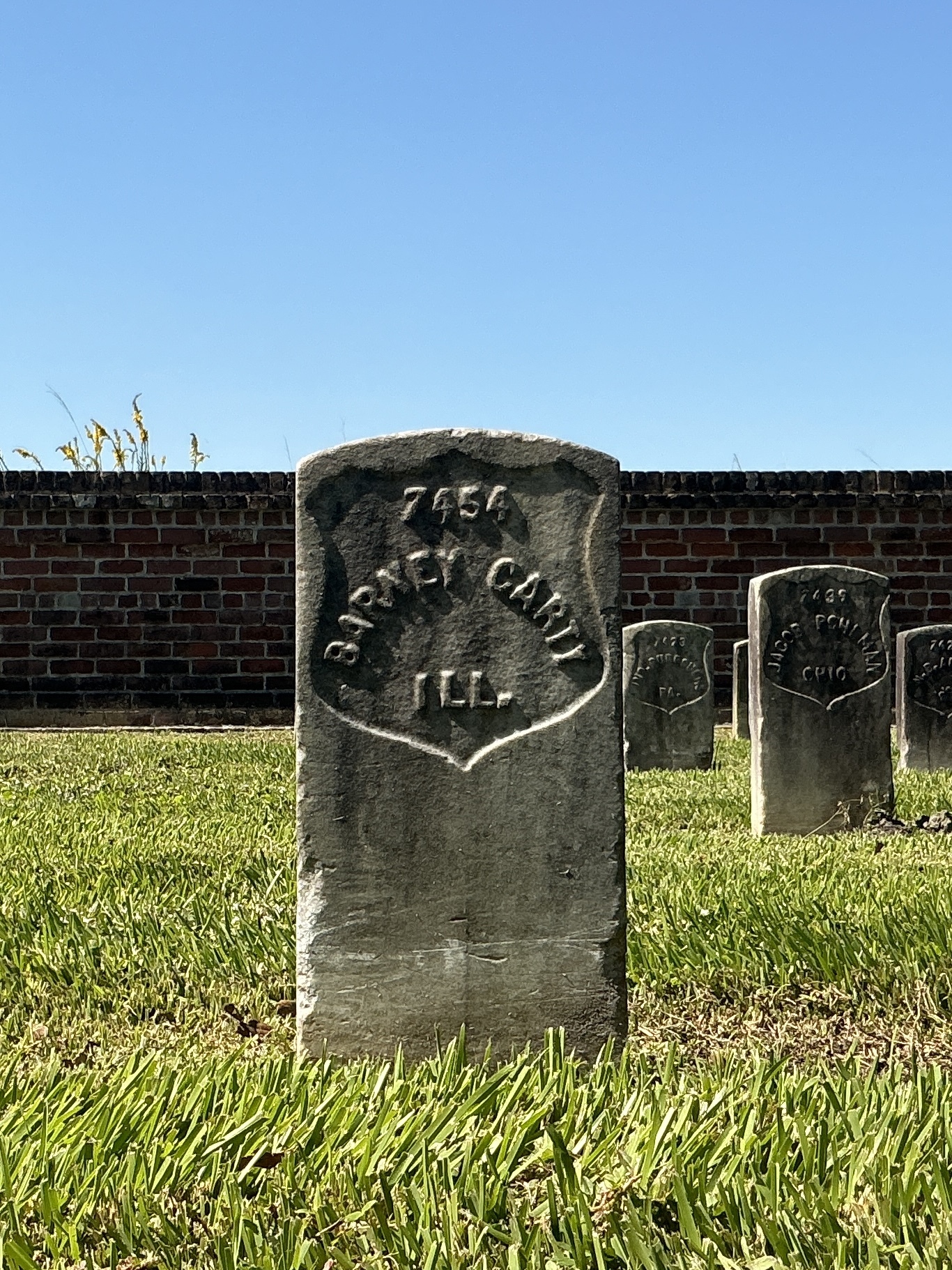 Front of historic upright marble headstone with recessed shield face.