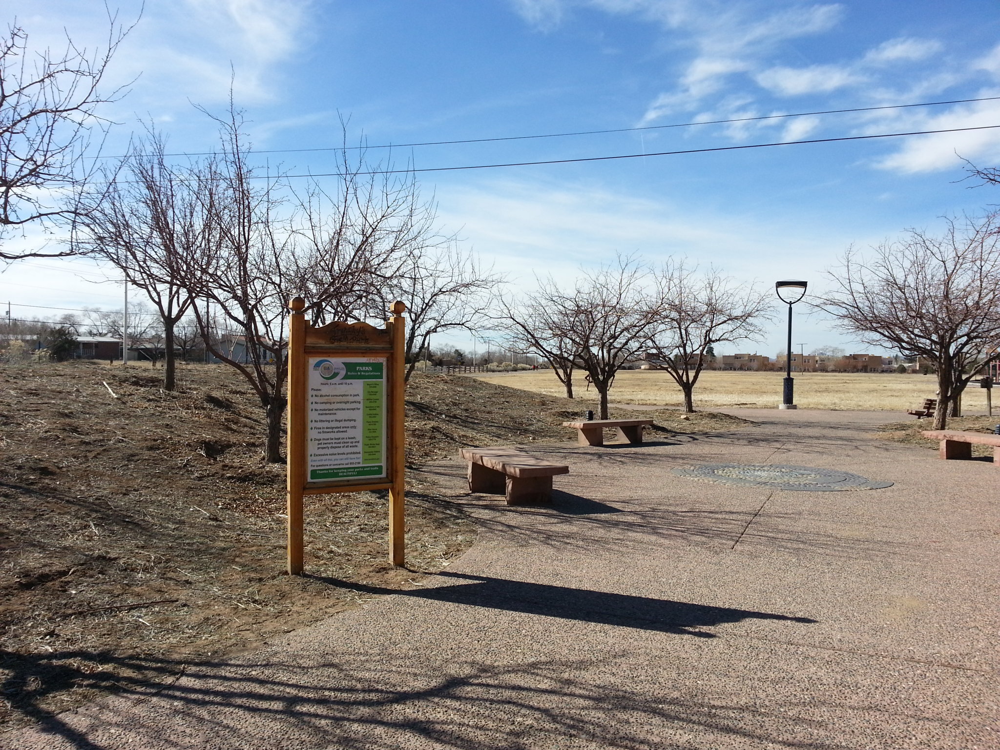 An open field with benches and a sign.