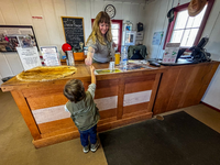 A ranger hands a junior ranger badge to a child over a front desk. 