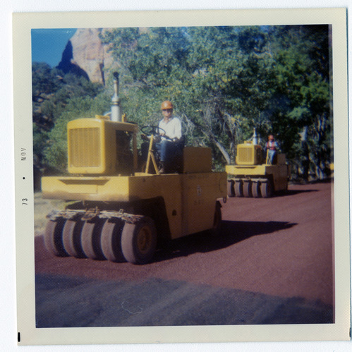 Men operating sealcoating vehicles during road repair.