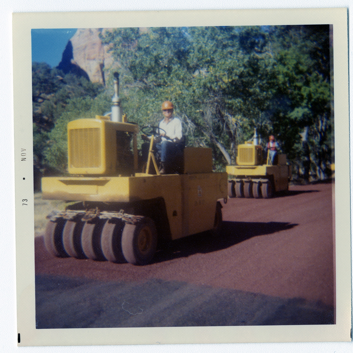 Men operating sealcoating vehicles during road repair.
