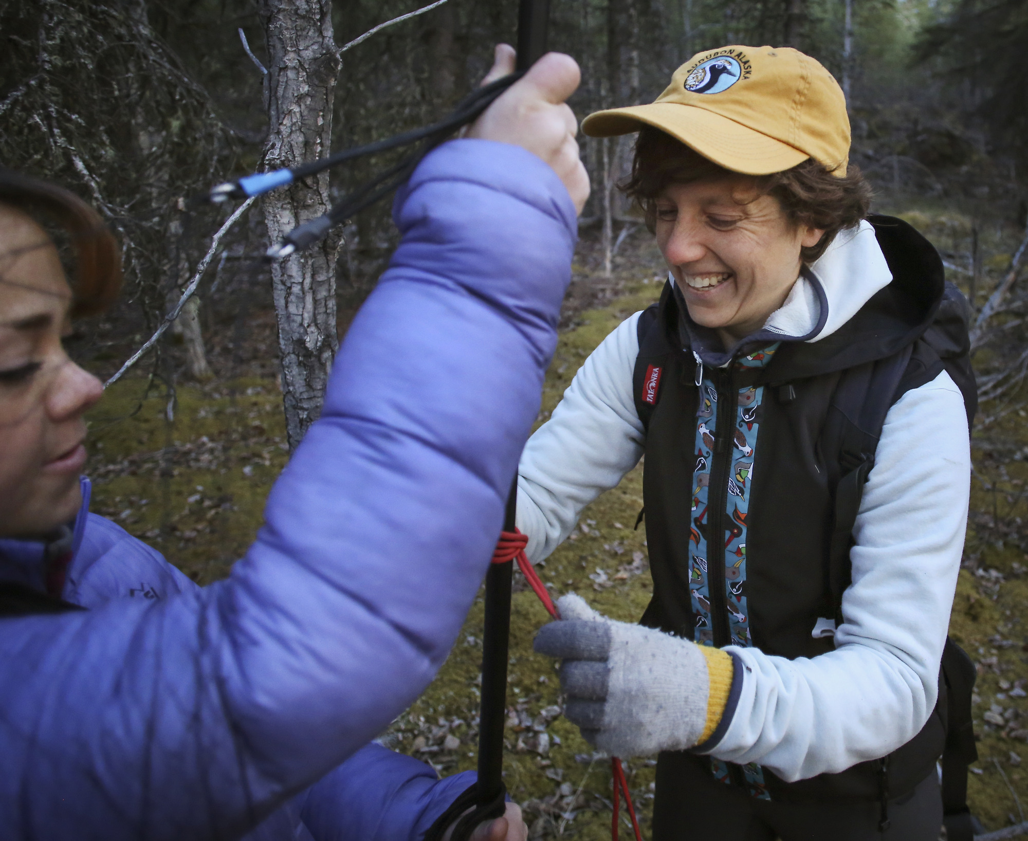 two women setting up a net in a forest