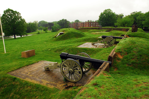 Hilly earthworks are covered in grass, two cannons line the earthworks. 