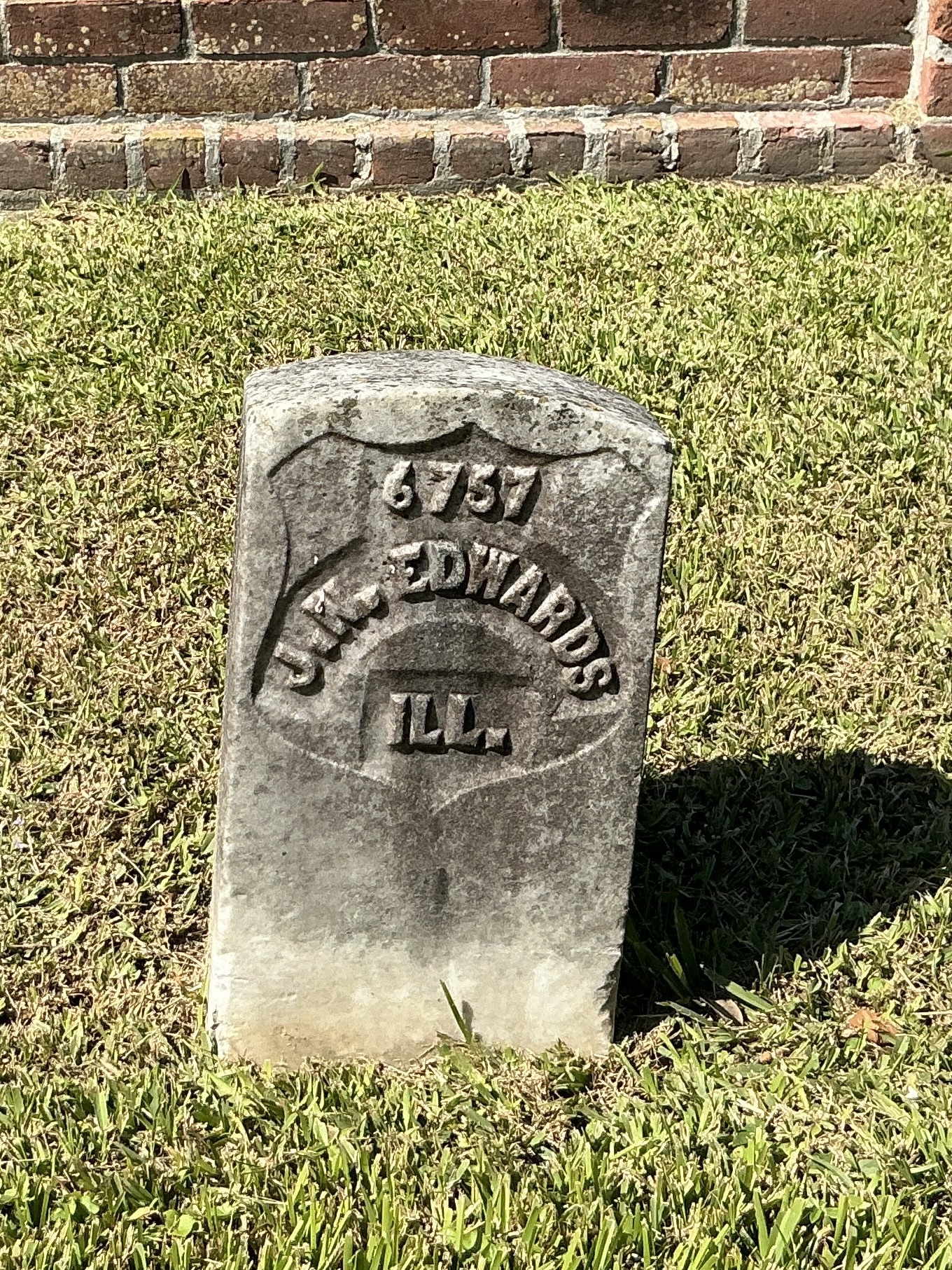 Front of historic upright marble headstone with recessed shield with recessed lettering face.