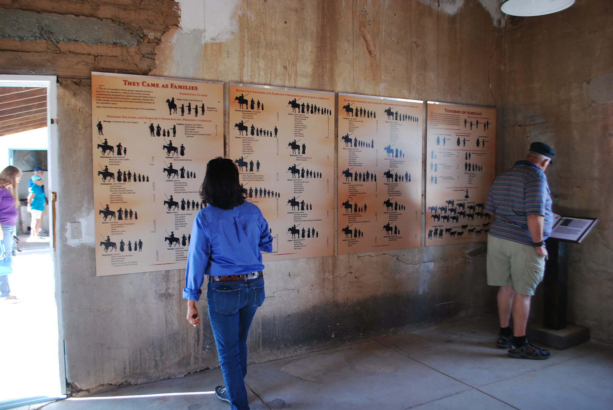 Two people read exhibit panels inside of a historic building