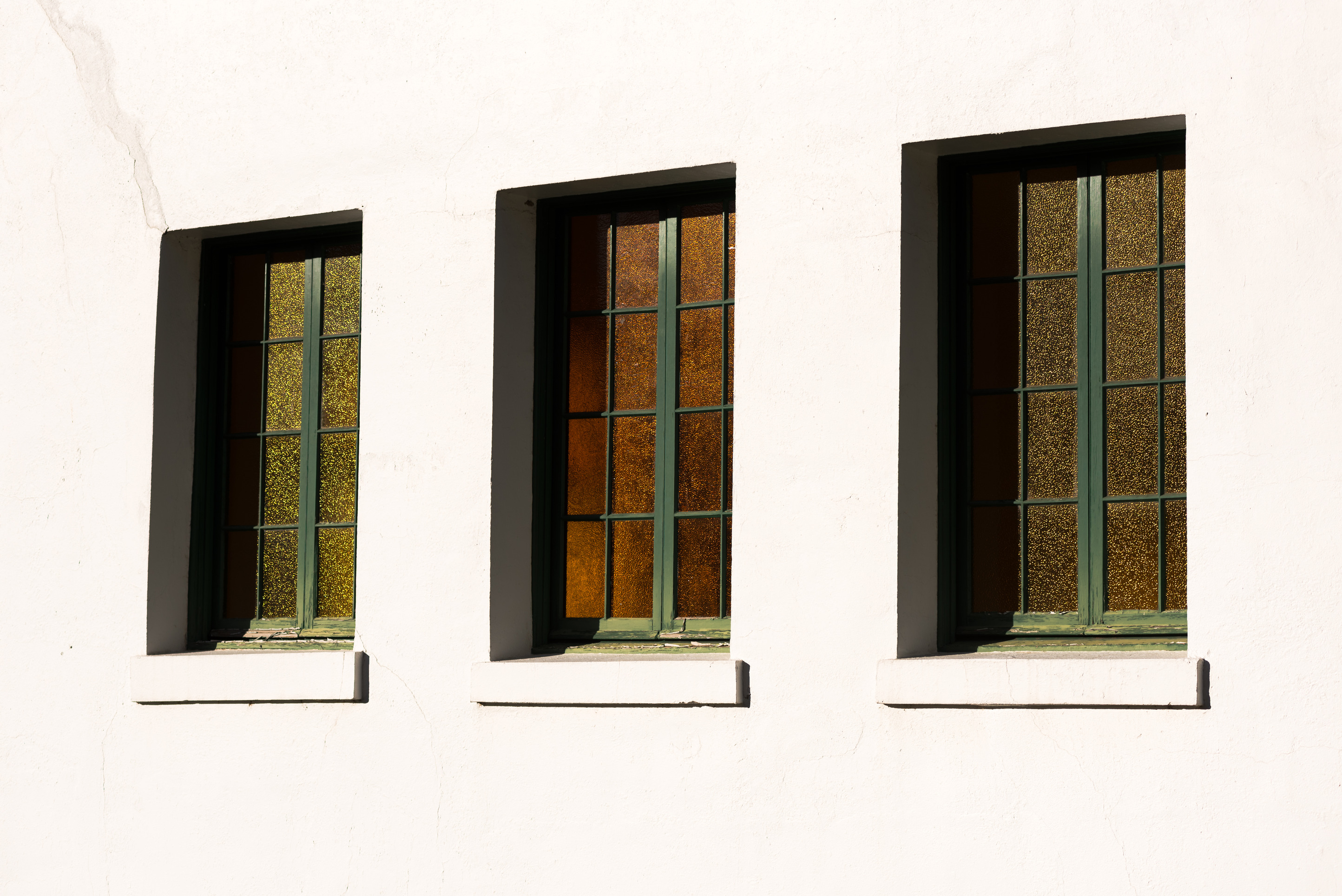 three windows with green paint on a white building