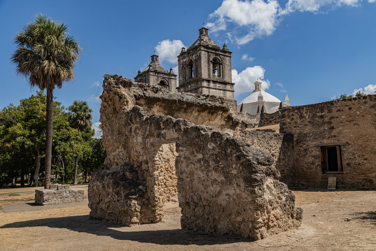 Stone ruins with the church bell tower in the background.