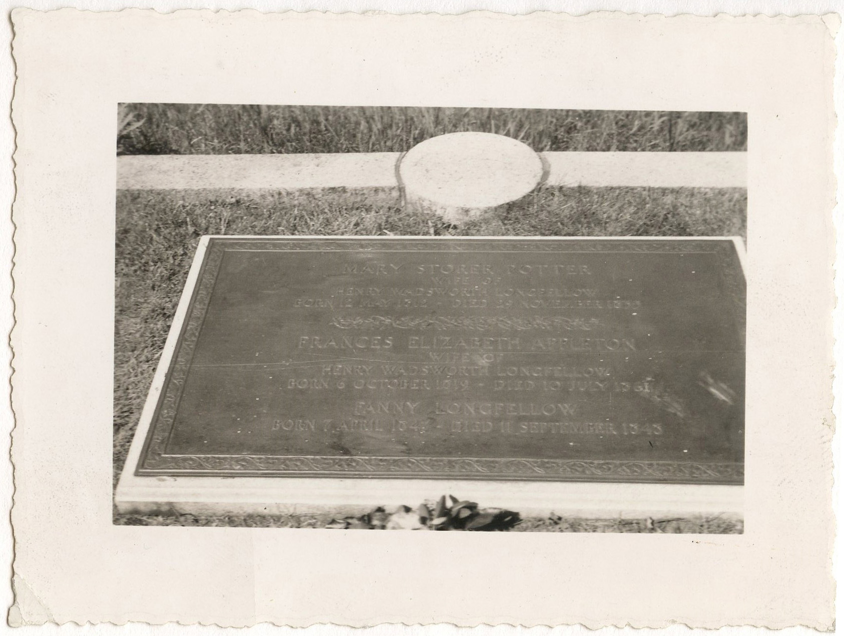 Close-up of metal memorial tablet to Henry Wadsworth Longfellow, Frances Elizabeth Appleton Longfellow, and Fanny Longfellow. Tablet set in stone in the ground and surrounded by grass.
