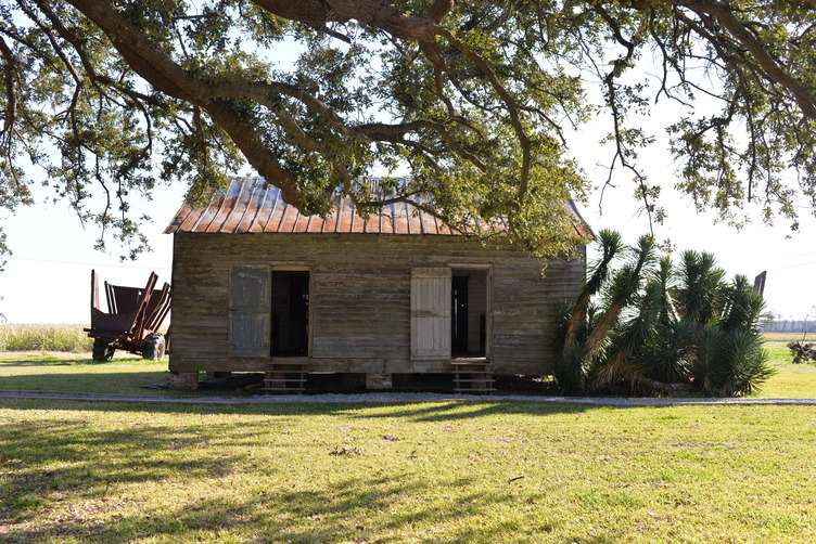 Wooden structure with two doors, short stairs leading to each, and a metal roof; it sits on short brick pillars.