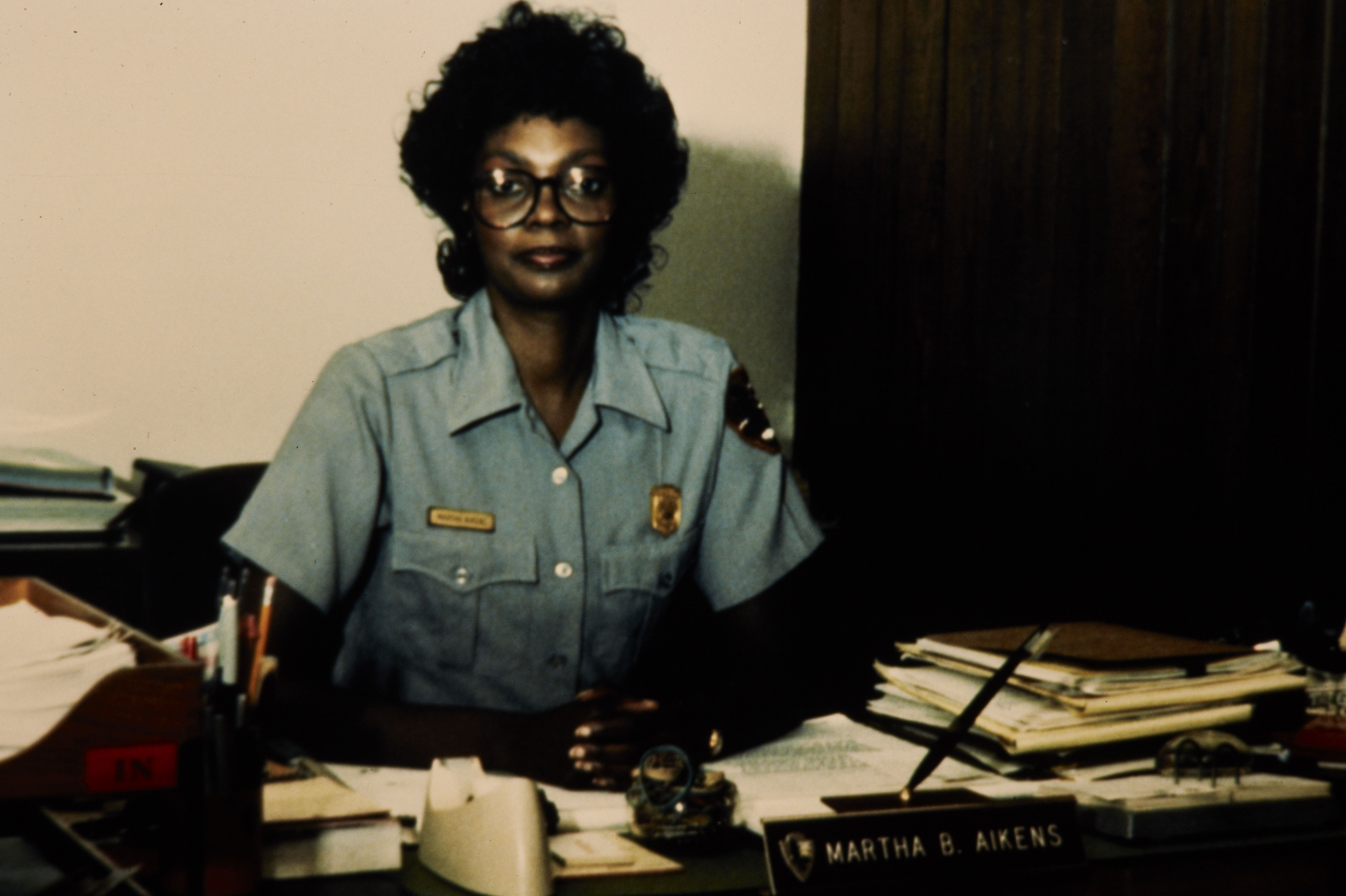 Martha B. Aikens wearing her NPS uniform looks up from her desk.