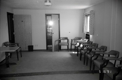Chairs along wall of living room area in barracks. [Image possibly for comparative housing study]