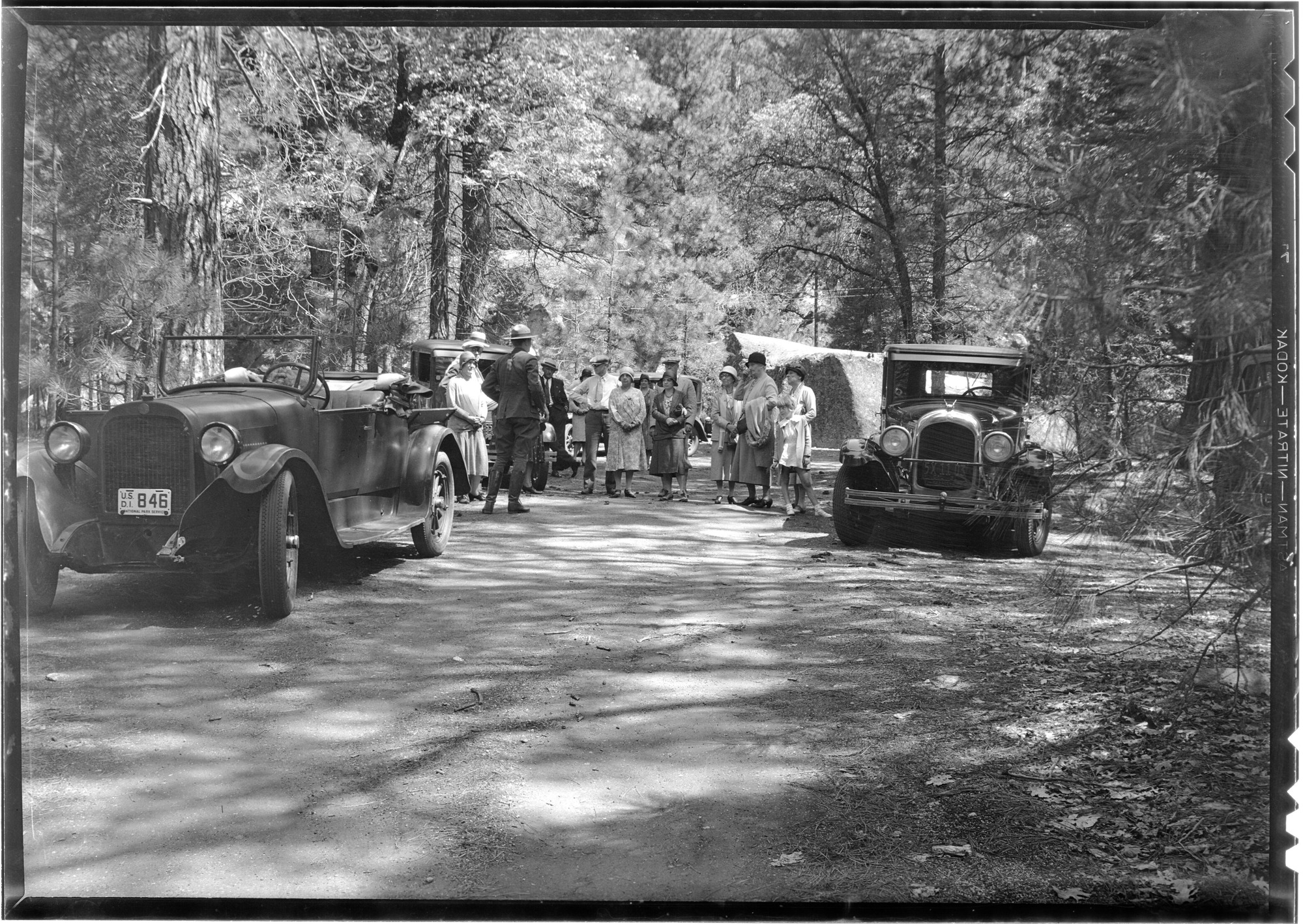 (group of people standing near cars)