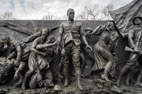 The aftermath depicts the physical and mental wounds of the fighters. Here are represented American women who served at home and on the fighting front. And here the turbulent, left-to-right narrative pauses, as the hero stops and looks directly at the viewer. The soldier’s look of shock and loss – the thousand-yard stare – along with the empty helmets piled at his feet, invite the viewer to stop and contemplate with him the costs of war.