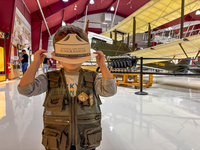 A child with a junior ranger cutout head band, behind him is a plane display. 