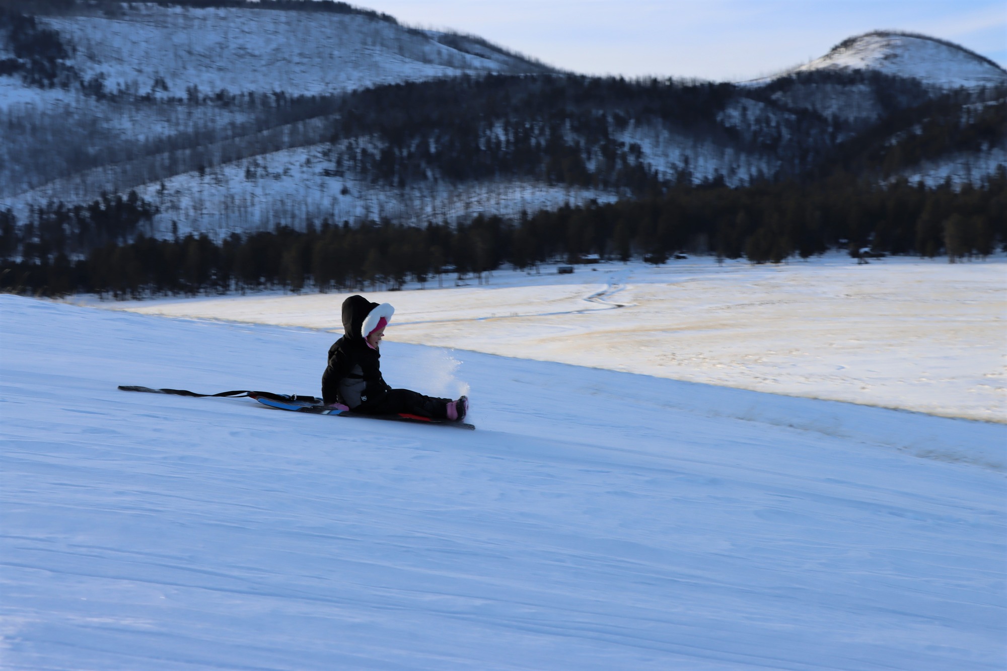 A child sledding down a snowy hill.