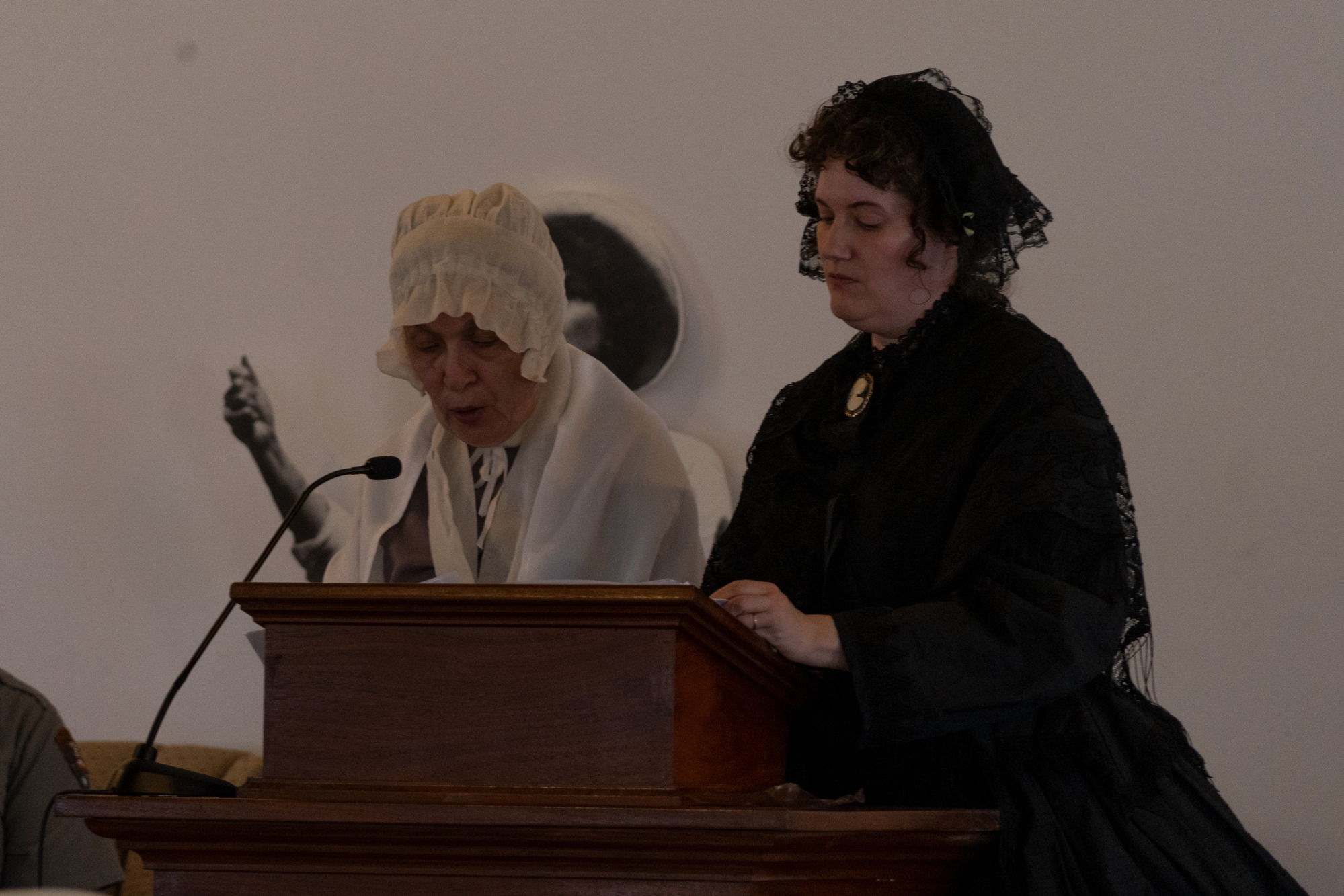 Living historians speak to an audience from a pulpit.