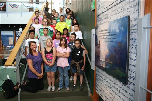 A group of students and their teacher pose on the stairs at the Heritage Center.