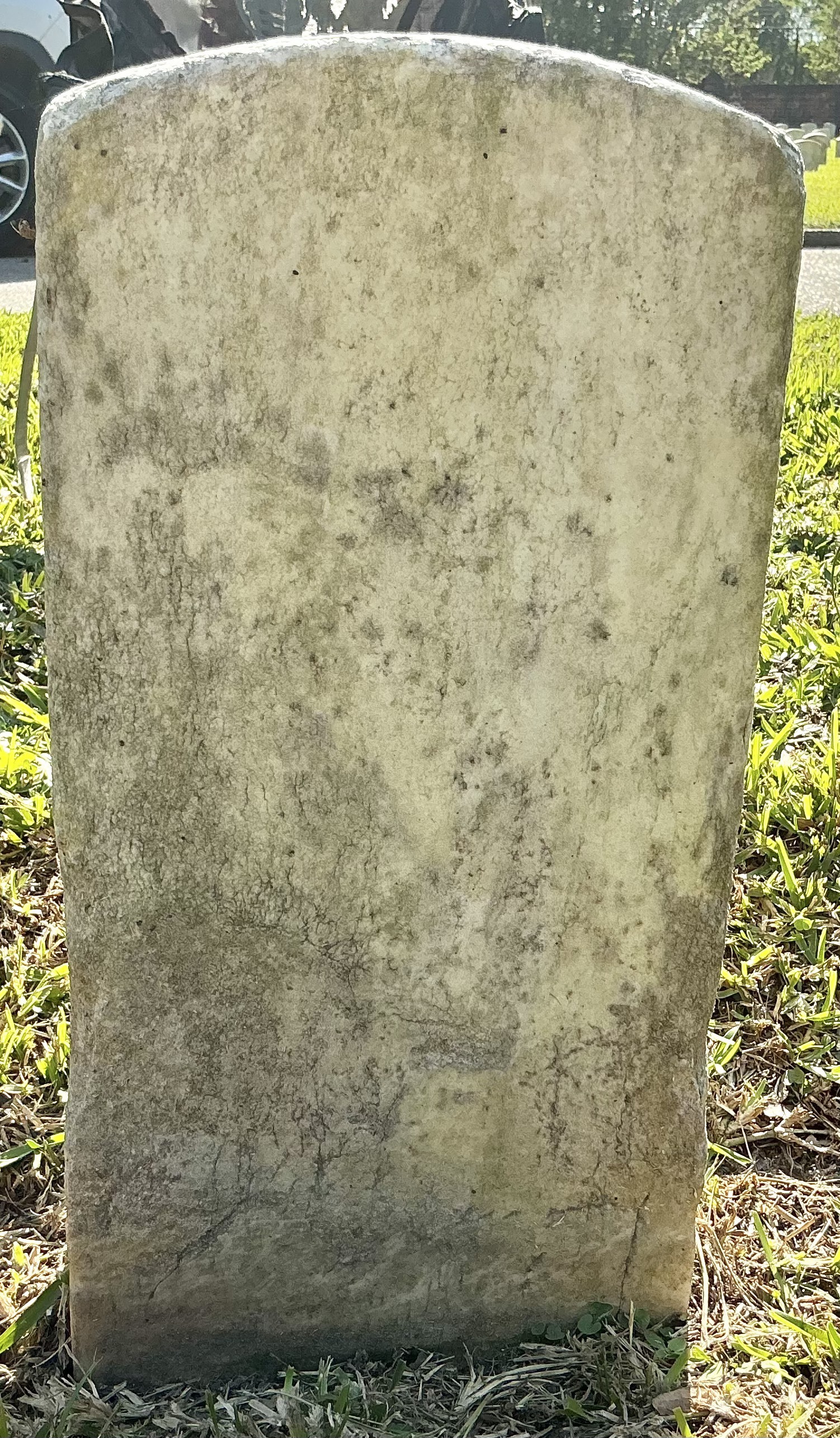 Back of historic upright marble headstone with recessed shield face.