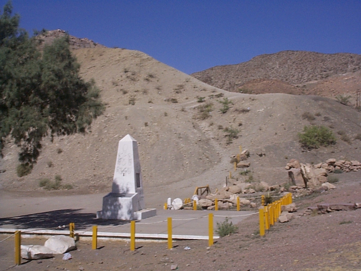 A white monument in the middle of a desert.