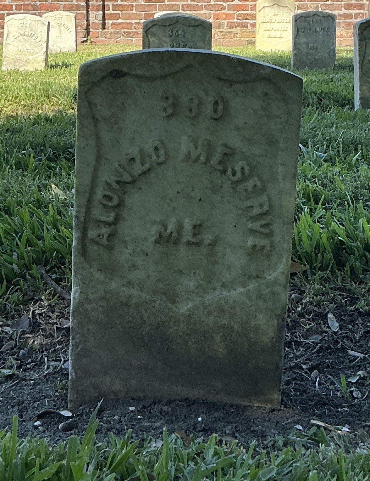 Front of historic upright marble headstone with recessed shield face.
