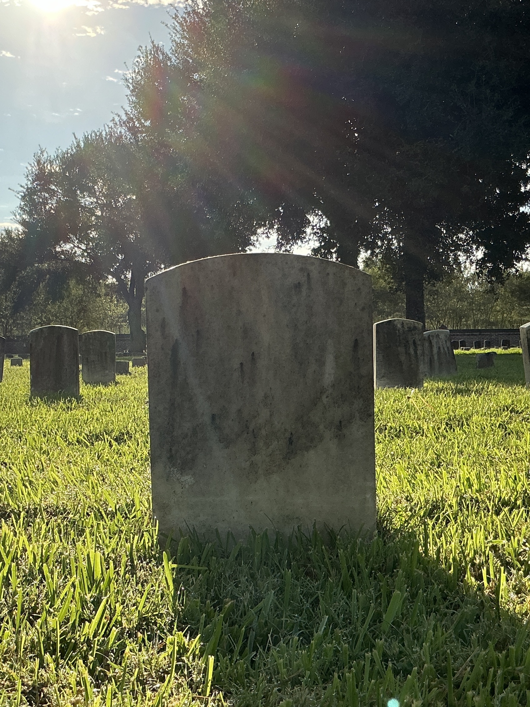 Back of historic upright marble headstone with recessed shield face.