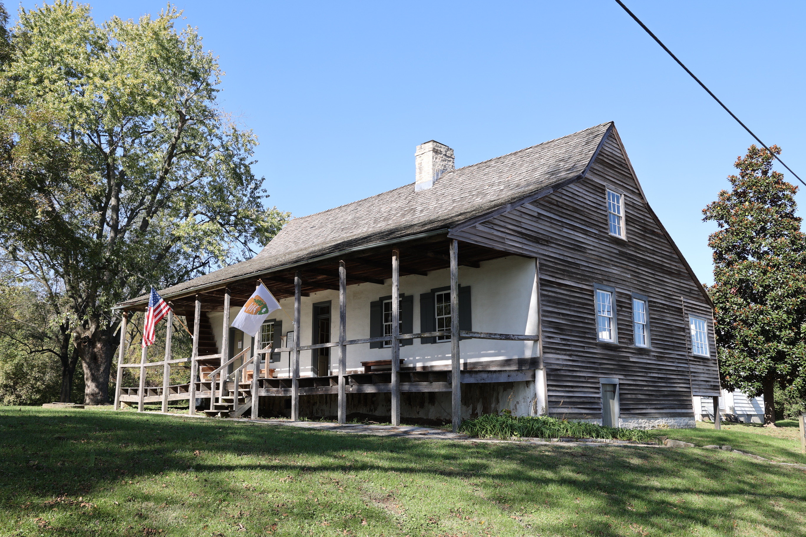 A house with a covered front porch, white front, plain wood siding and shingles.