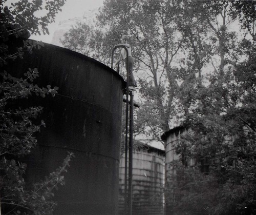 Woman standing at top of water tank ladder prior to start of reroofing project.