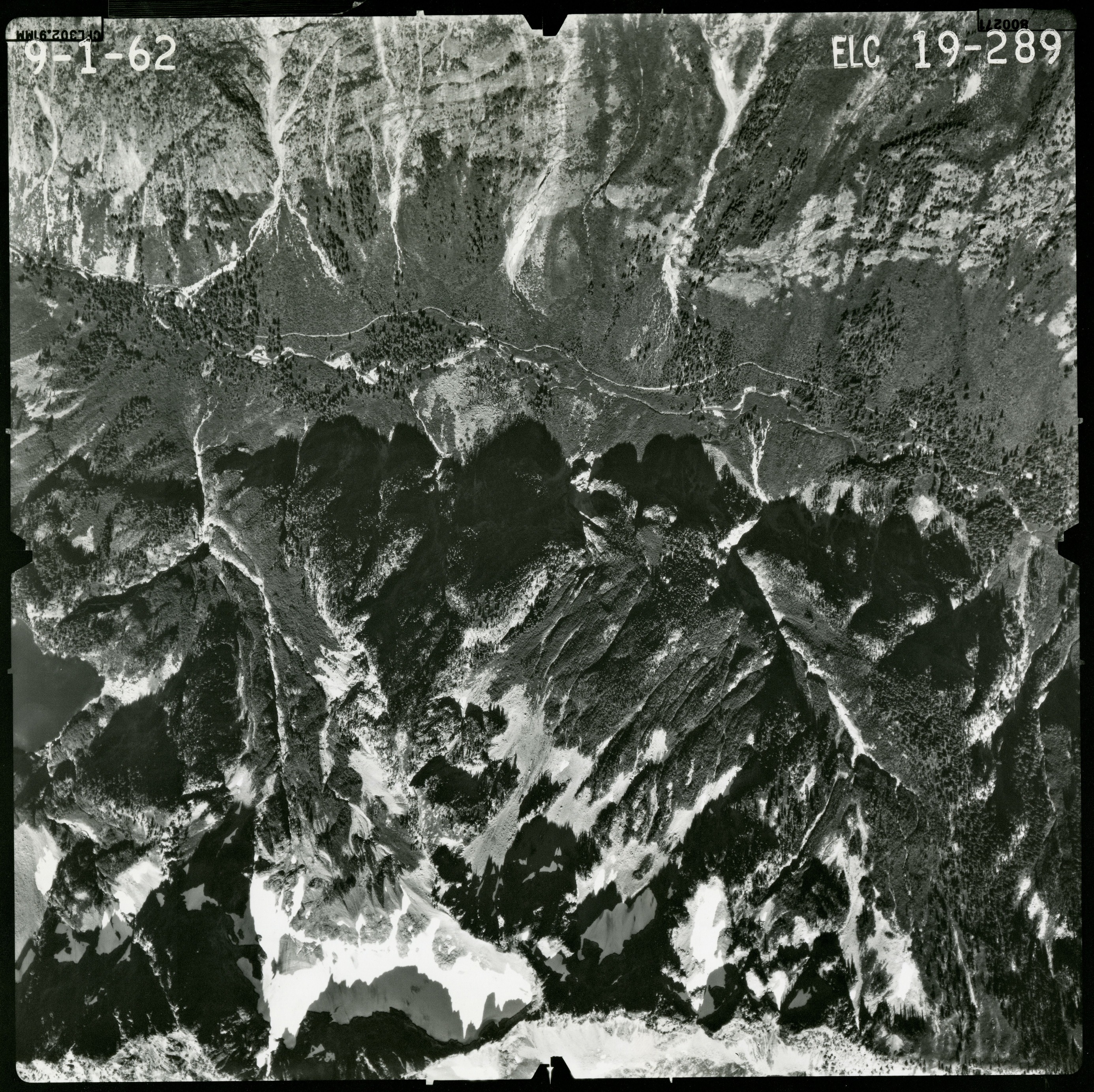 Black and white aerial photograph of glaciated mountain peaks and valleys.