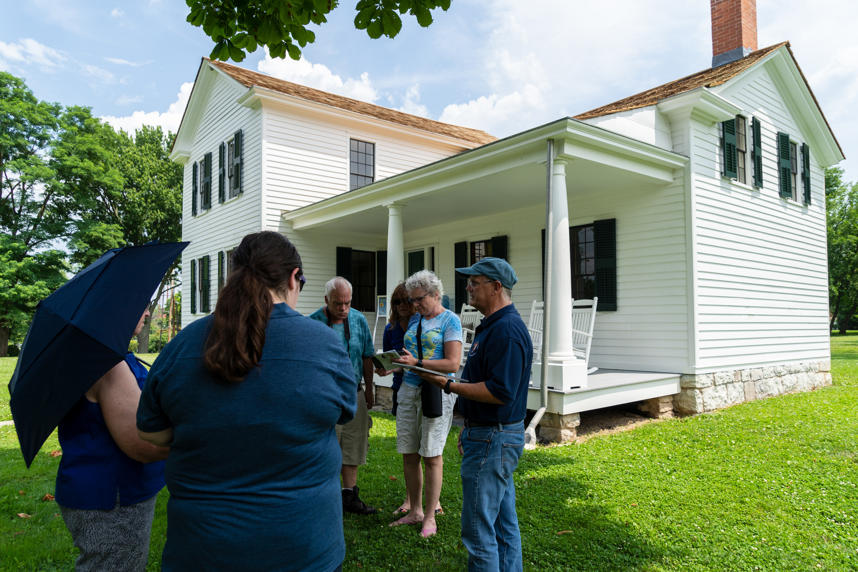 A group of people stand in front of a historical home.