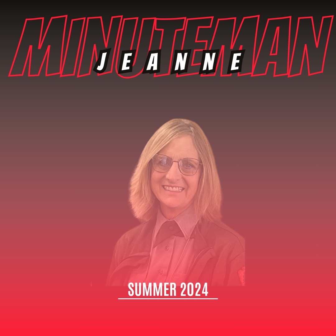 Woman with shoulder-length blonde hair and glasses wearing a green sweater. Words "Minuteman Jeanne Summer 2024"